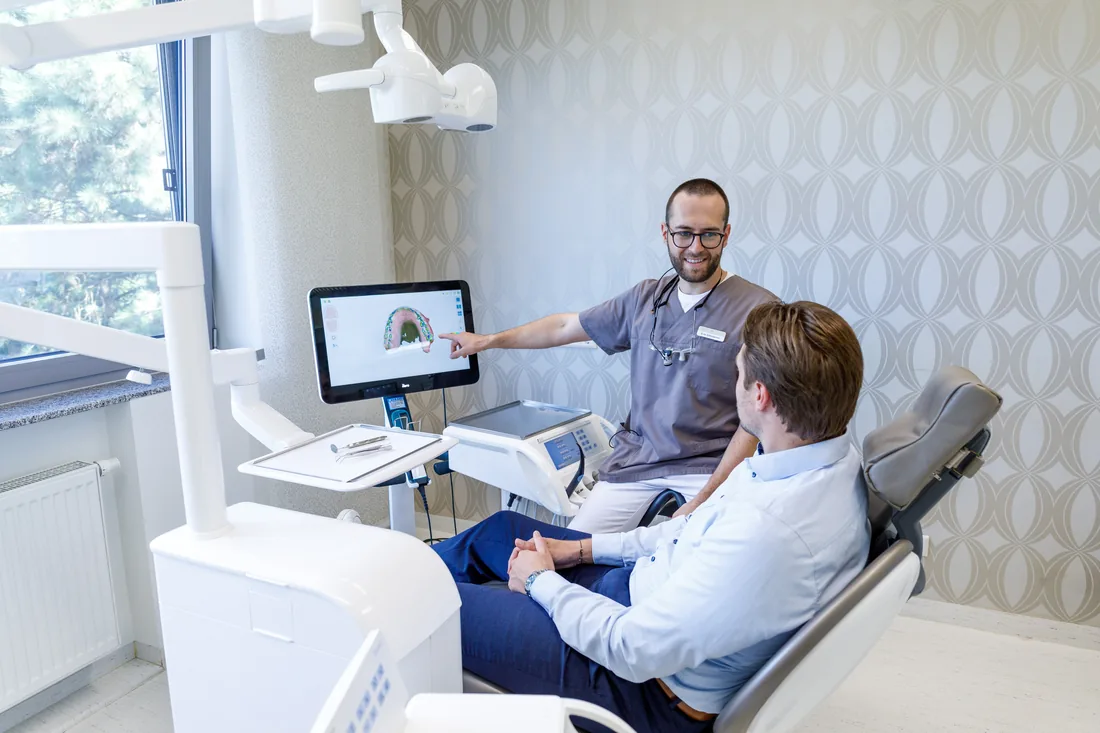 ZA Erik Sillmanns erklärt einem Patienten den digitalen Scan seines Kiefers am Bildschirm